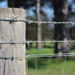 Traditional galvanized double barbed wire fence mounted on wooden posts for farm boundary | ANJIA