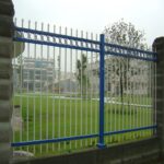 Blue and white powder coated steel palisade security fence with decorative rings, installed in industrial park lawn perimeter protection | ANJIA