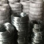 Multiple stacked hot dipped galvanized steel binding wire coils stored in factory warehouse for bulk export | ANJIA