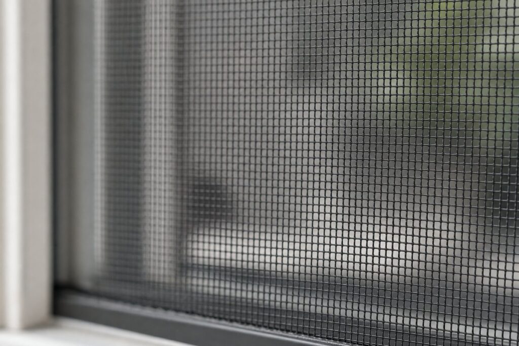 Charcoal fiberglass window screen mesh close-up showing 18x16 weave pattern and PVC-coated yarns