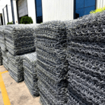 Bulk stacked hot dipped galvanized gabion mattress rolls and sheets stored in factory warehouse for wholesale hydraulic engineering supply | ANJIA