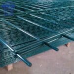 Bulk stock of hot dipped galvanized double wire welded mesh fence panels stacked in factory warehouse for wholesale export | ANJIA