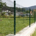 Long distance green PVC euro fence installed on outdoor lawn with concrete posts for site perimeter security | ANJIA