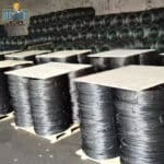 Pallet stacked coils of soft black annealed binding wire stored in factory warehouse for bulk export | ANJIA