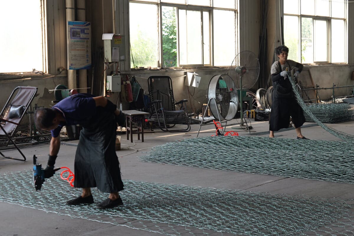 Worker checking wire mesh opening during onsite inspection